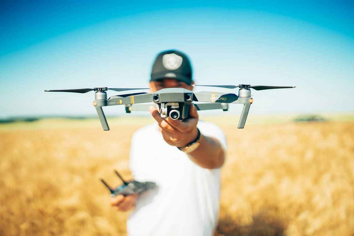 Persona sosteniendo un dron en un campo de trigo