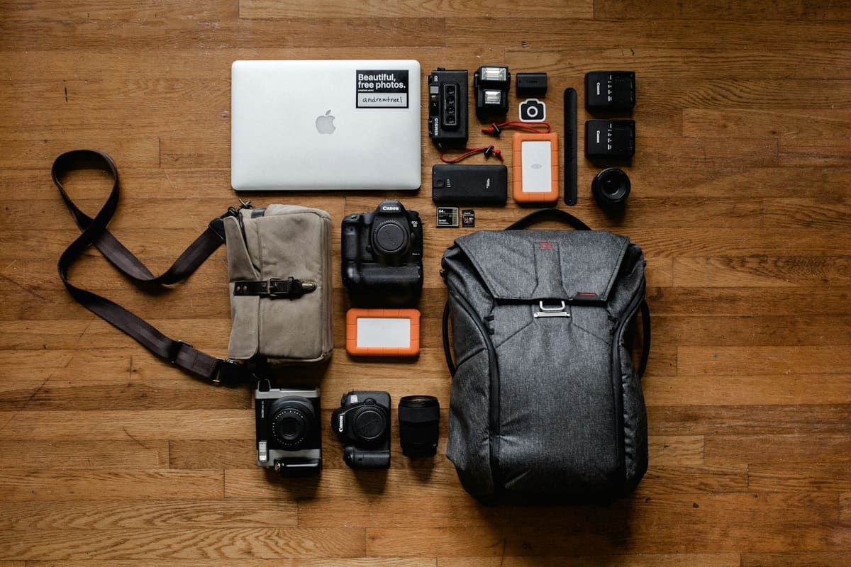 Notebook, cámaras de fotos y mochila sobre un piso de madera
